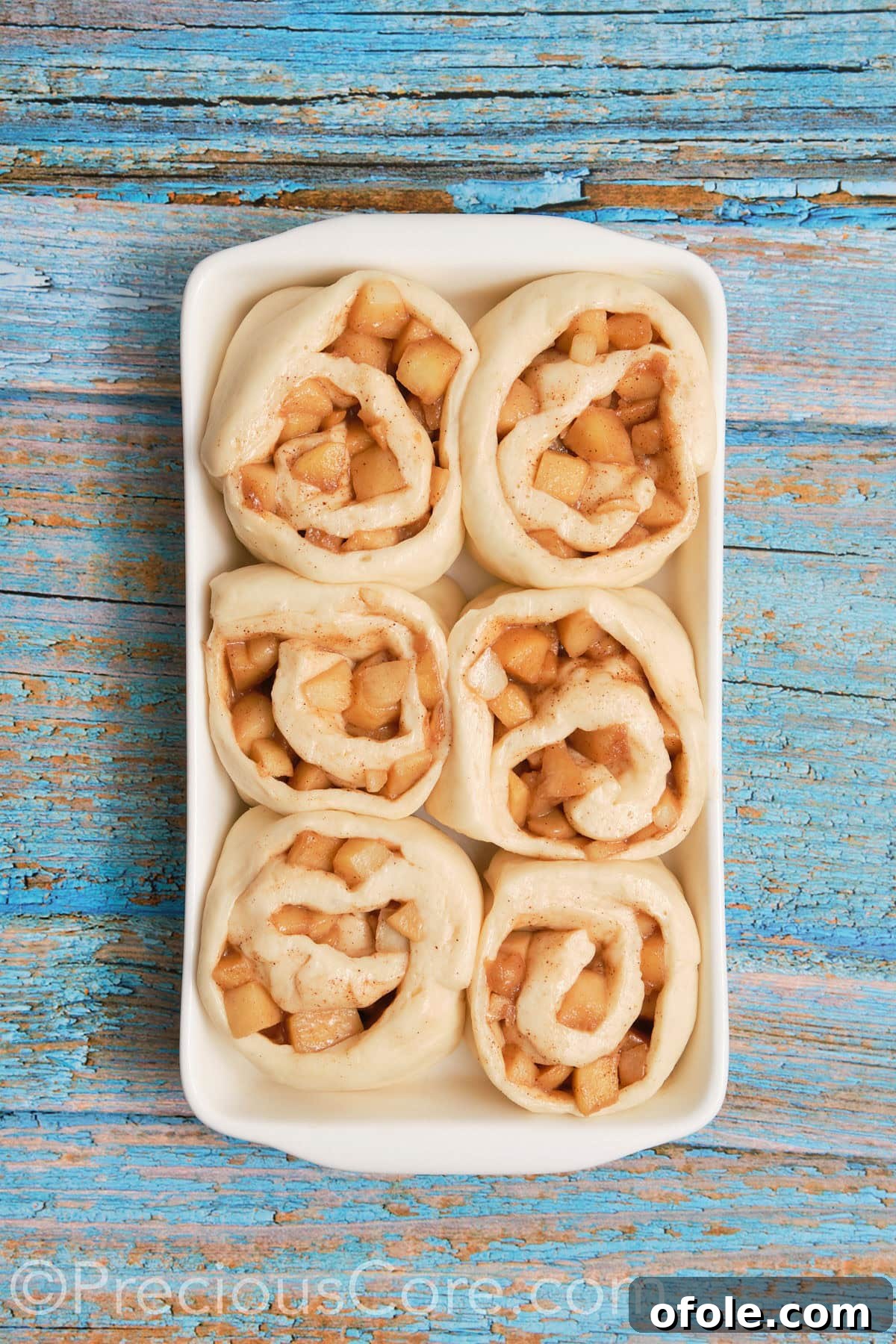 Apple cinnamon rolls in a baking dish after completing their second rise, looking puffy and expanded.