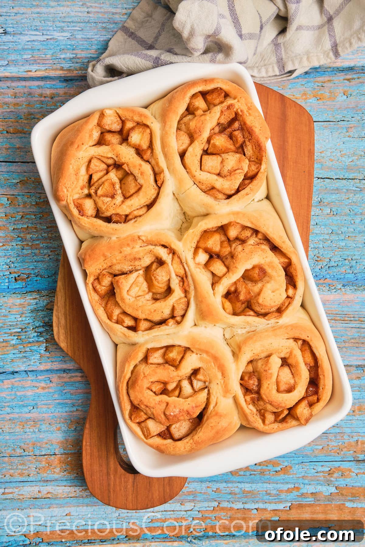 Freshly baked homemade Cinnamon Rolls With Apple Pie Filling, golden brown and perfectly risen in a baking dish, just out of the oven.