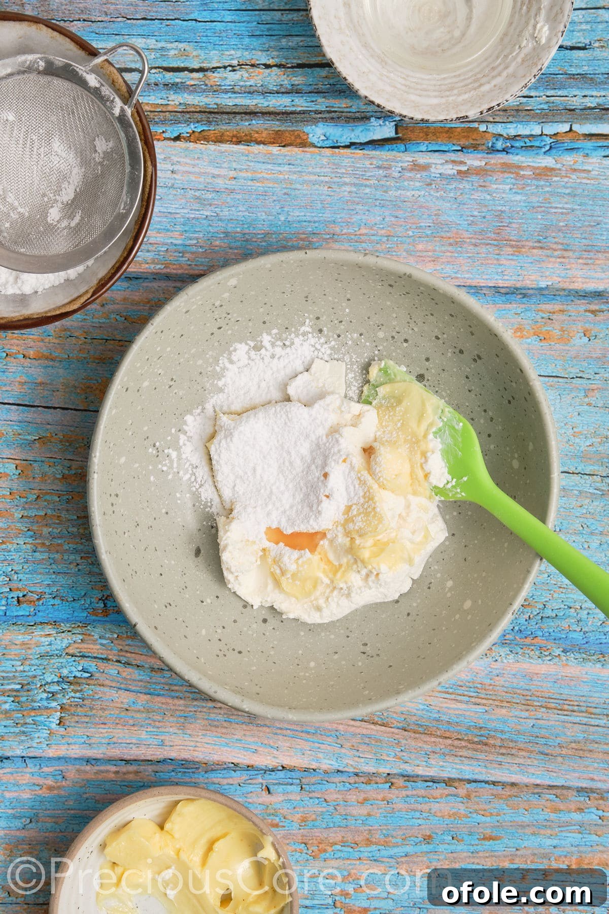 All ingredients for the cream cheese frosting (cream cheese, butter, powdered sugar, vanilla) placed in a mixing bowl before whipping.