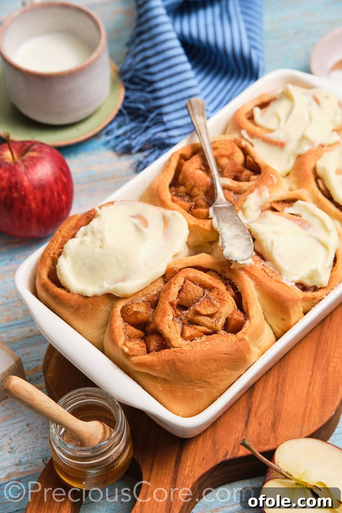 A beautiful side shot of golden-brown homemade apple cinnamon rolls, showcasing their tender layers and generous frosting.