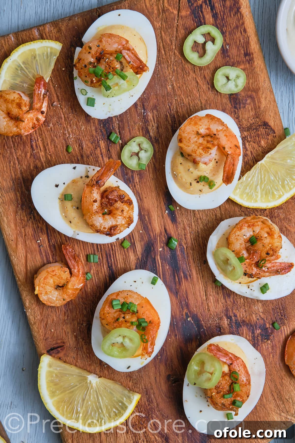 Cajun Shrimp Deviled Eggs 2 Deviled eggs with shrimp on a chopping board.