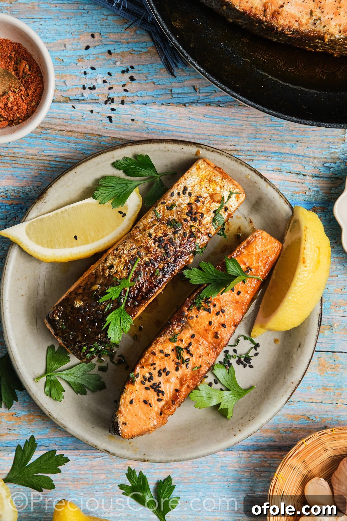 Cooked salmon on a plate garnished with fresh parsley and lemon.