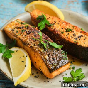 Cajun Honey Butter Salmon on a plate, garnished with fresh herbs and lemon.
