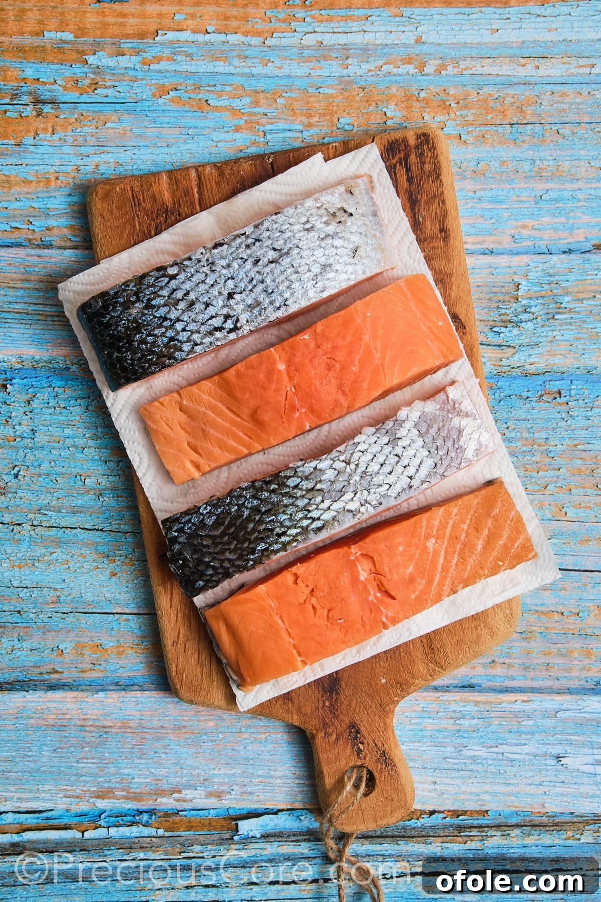 Patting salmon dry with paper towels to remove moisture.