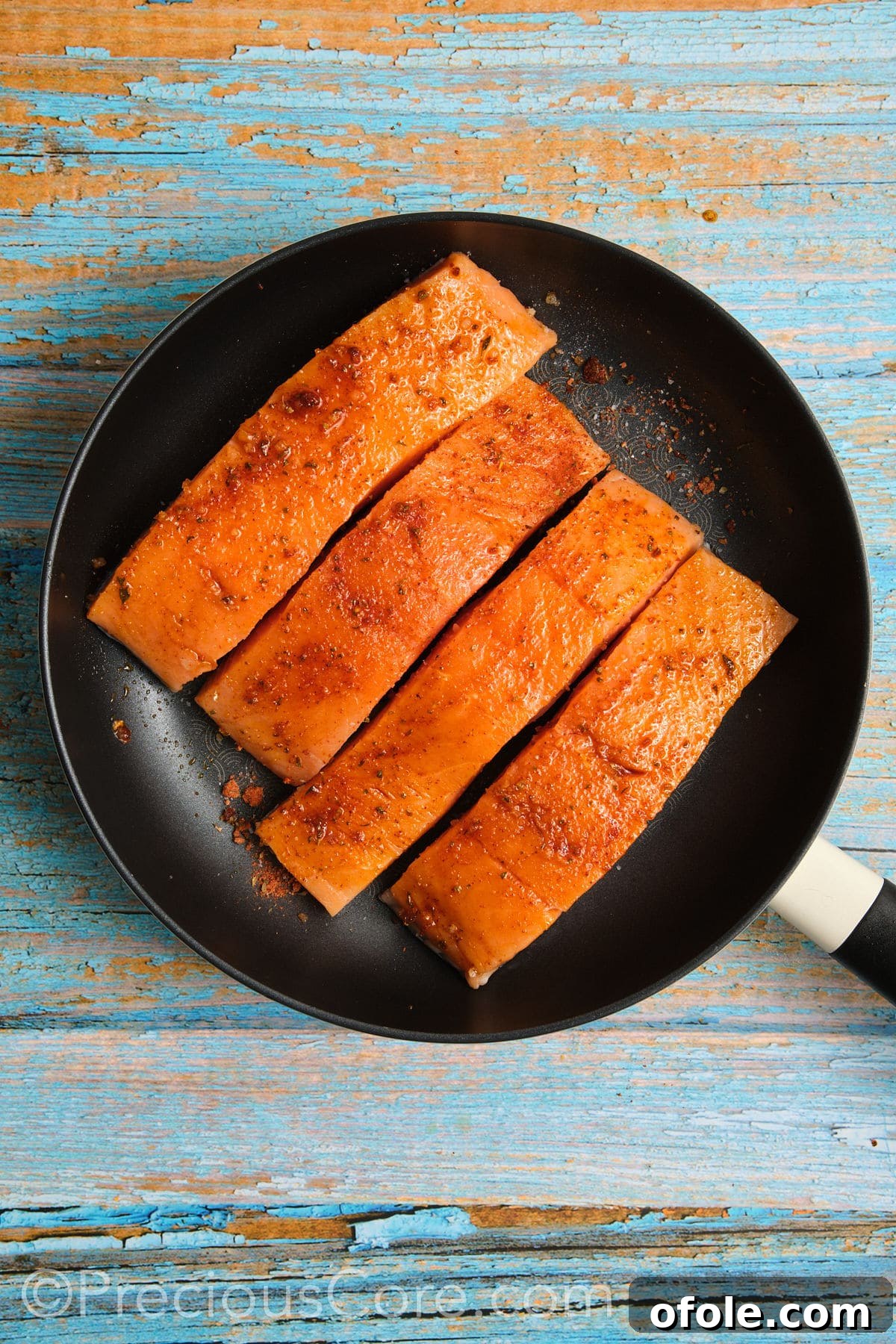 Salmon cooking skin-side down in a hot skillet.