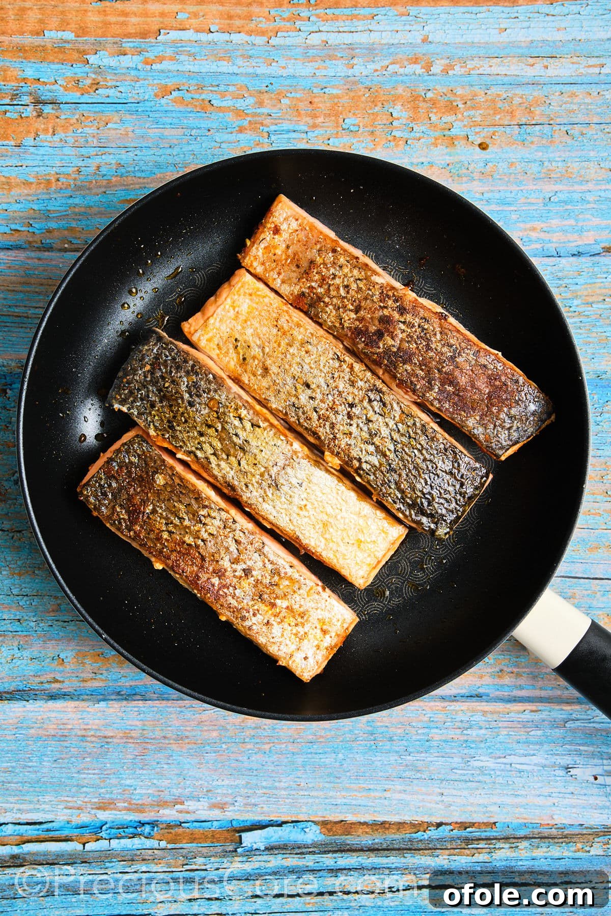 Salmon flipped to the other side, continuing to cook in the skillet.