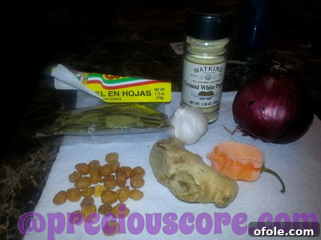 A collection of fresh ingredients and aromatic spices, including golden Njansa nuts, prepared for Pepper Soup.