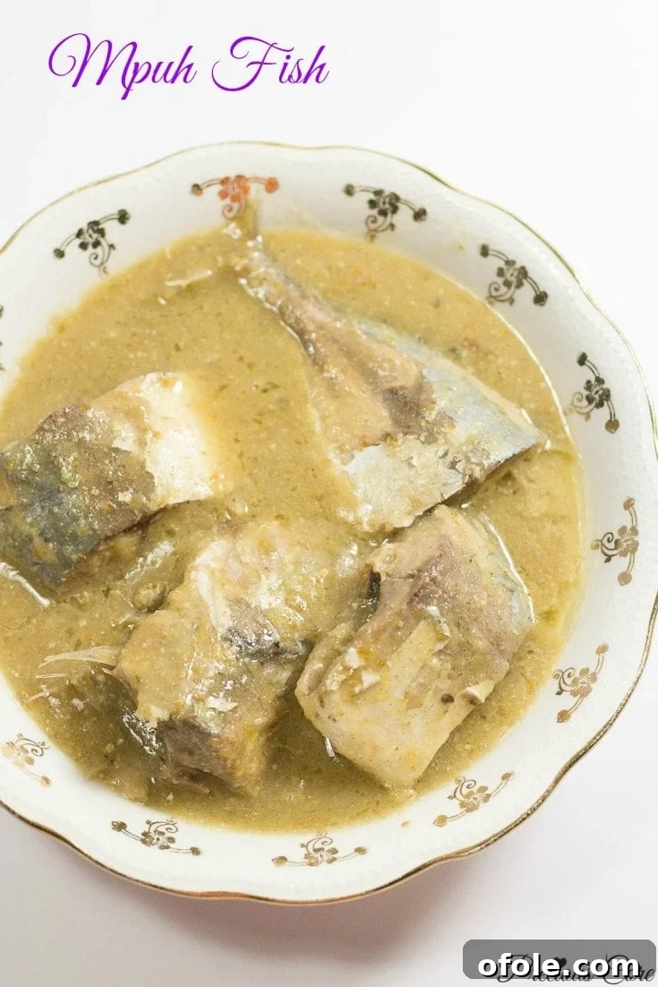Mpuh fish in a bowl. A creamy white sauce with pieces of fish, garnished.
