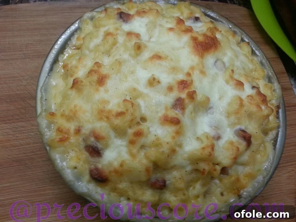 Homemade baked Mac and Cheese with sausage and potatoes in a cake pan.