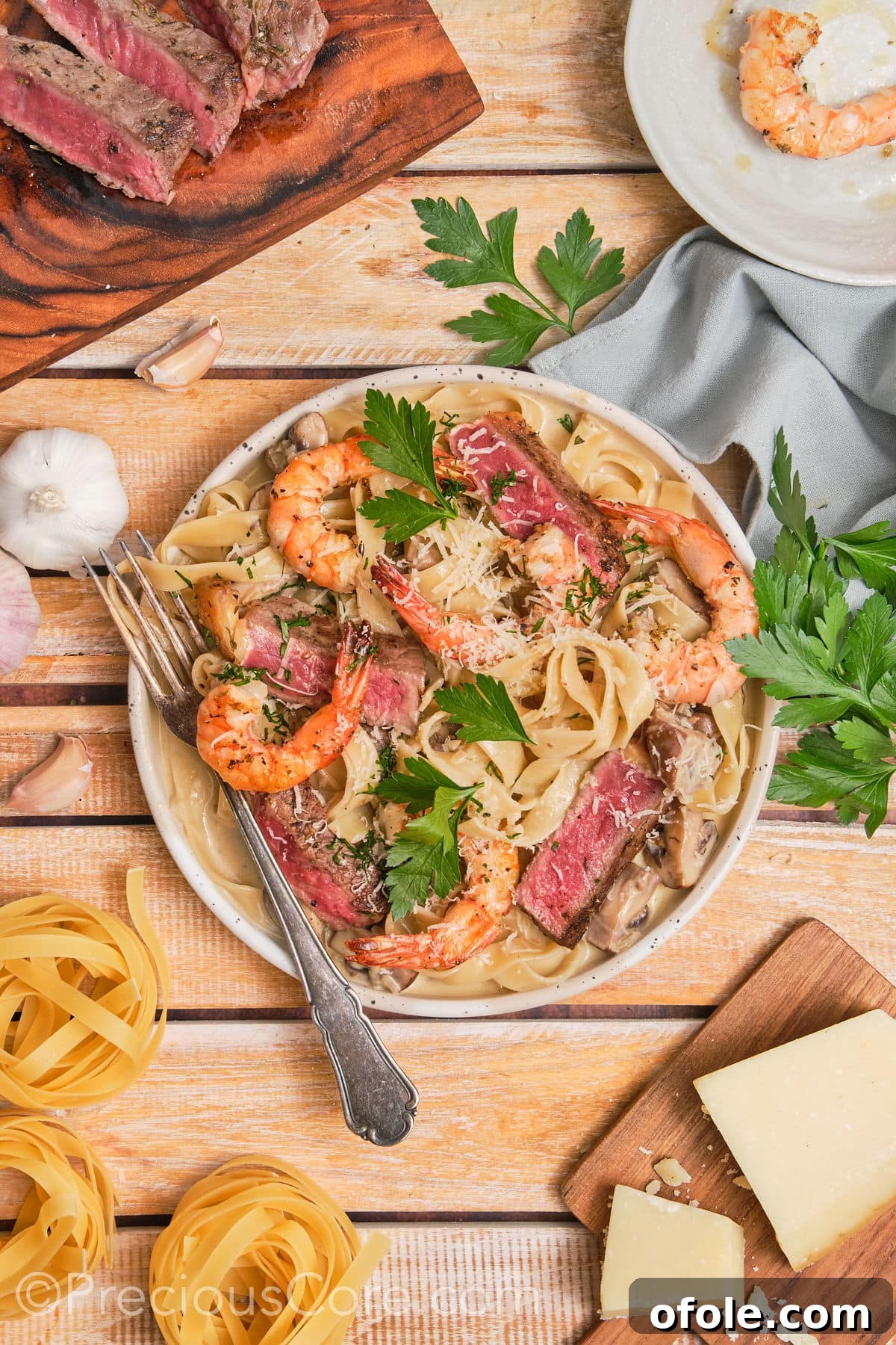 Land and Sea Pasta 4 Wide shot of steak and shrimp pasta on a plate.