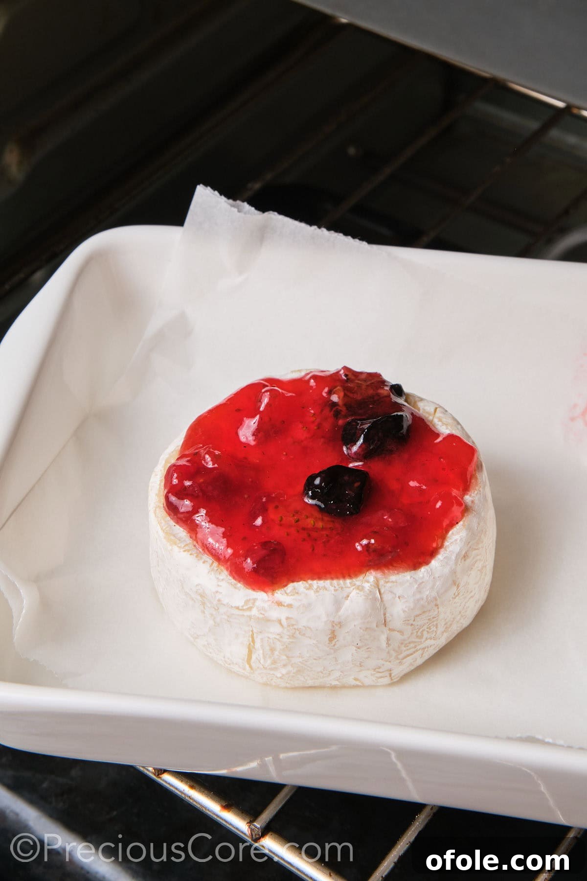 Brie with preserves baking in a baking dish, cheese softening.