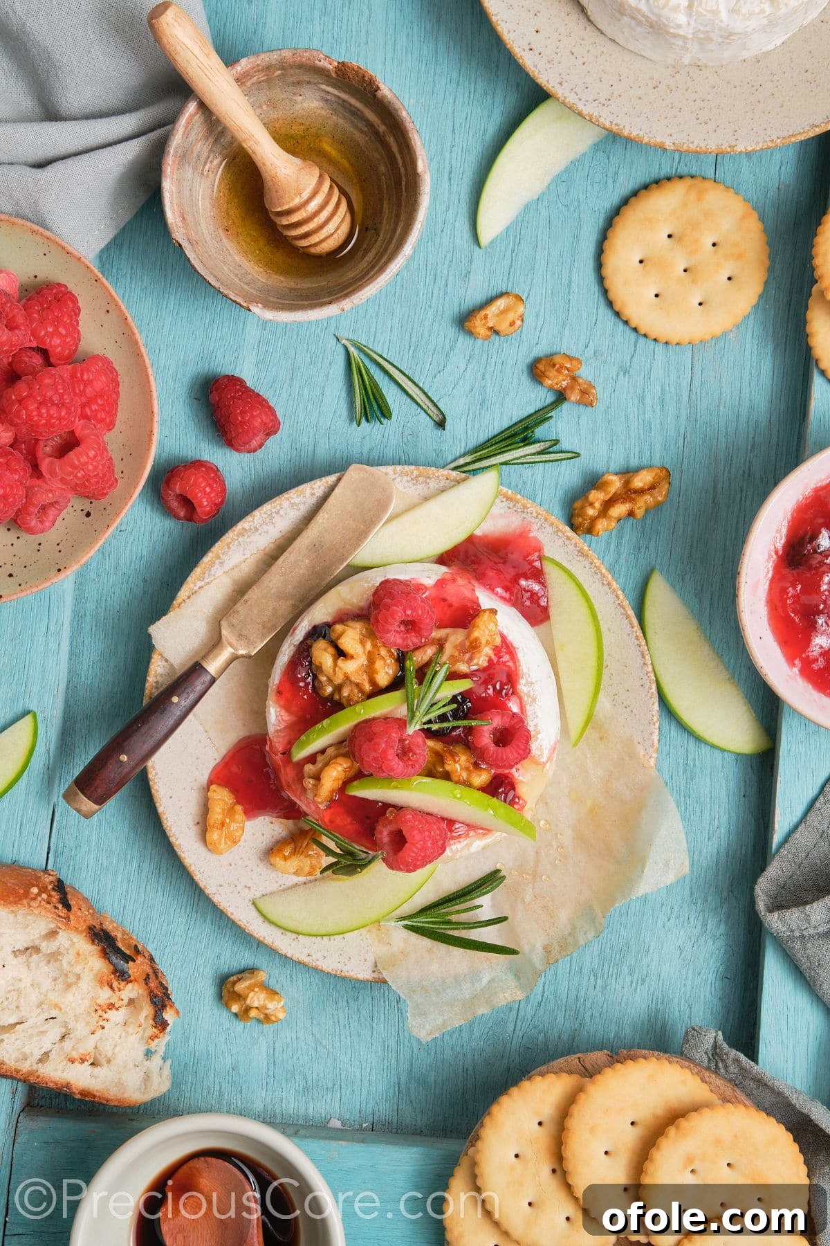 Beautifully garnished baked brie and preserves with fresh raspberries, apple slices, and candied walnuts.