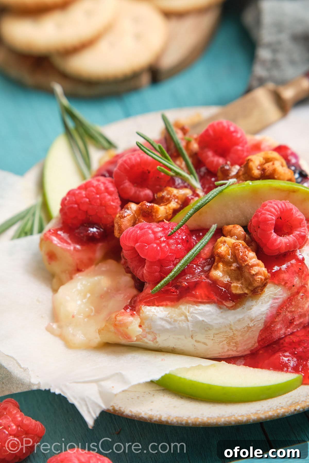 Served baked brie and preserves with gooey cheese center, ready to be enjoyed with crackers.