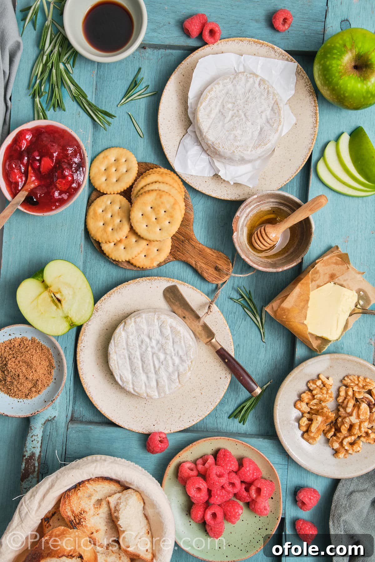 All ingredients for baked brie and preserves laid out on a wooden board.
