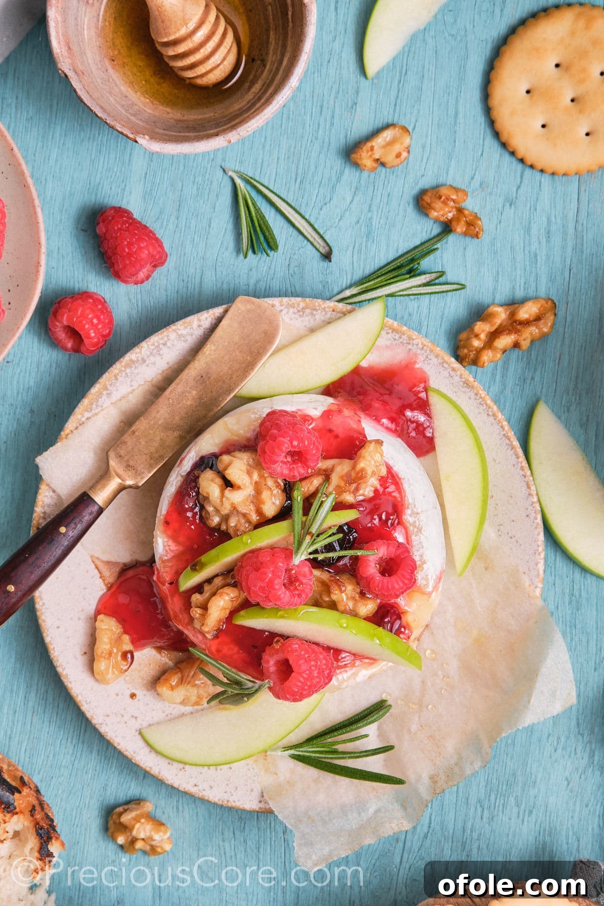 Served baked brie and preserves with fresh fruit and crackers on a rustic board.