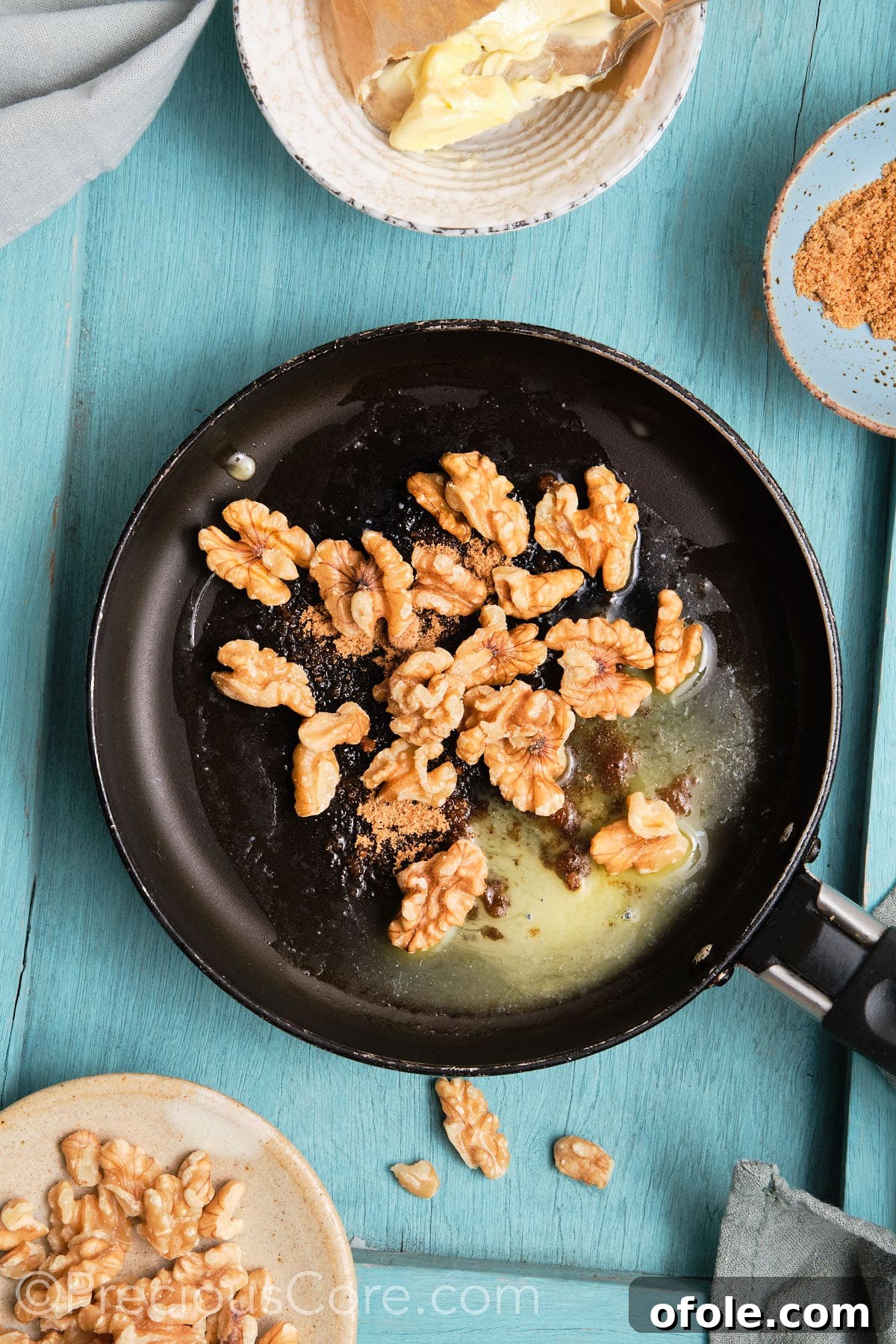 Walnuts cooking in a skillet with brown sugar and butter, starting to caramelize.