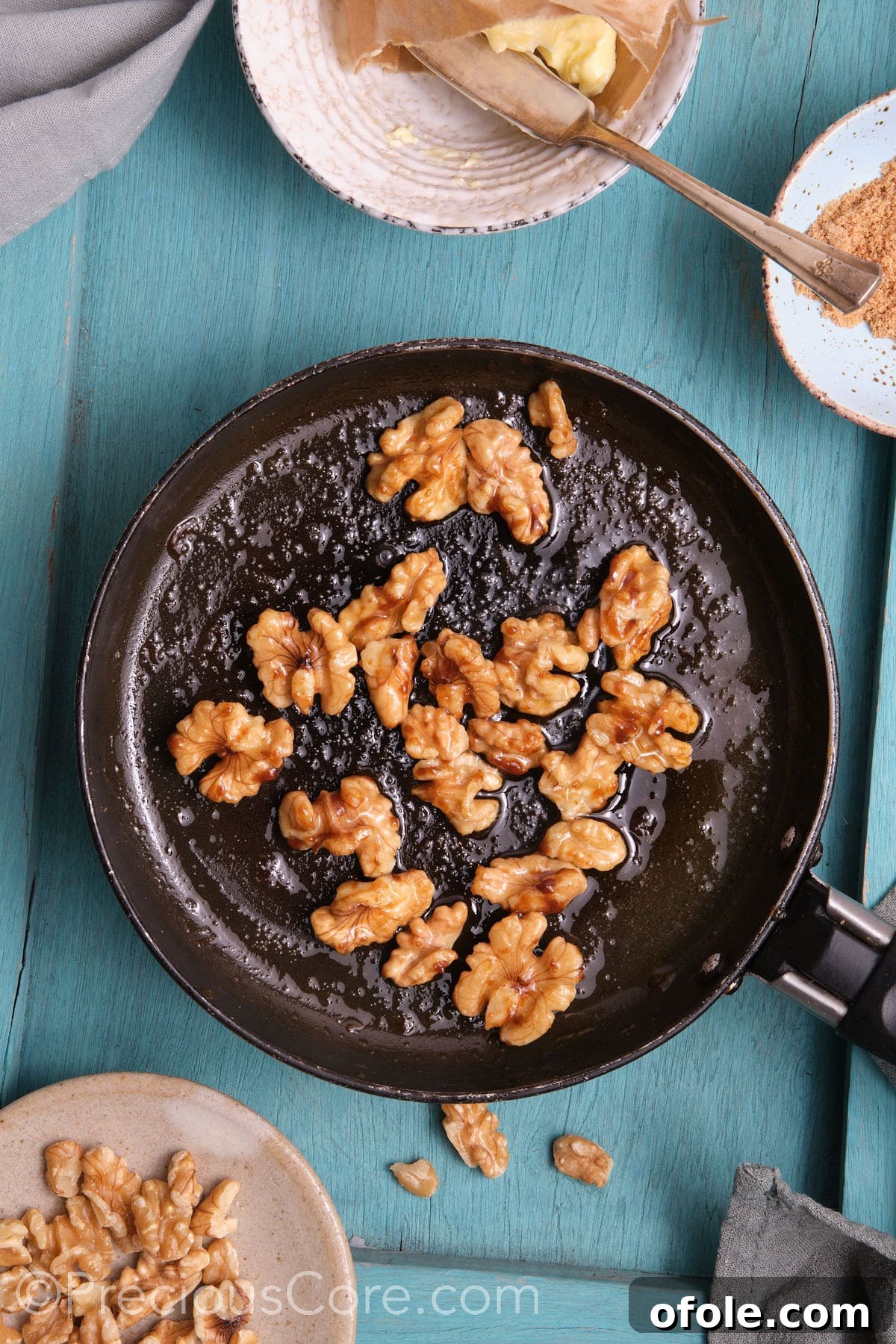 Caramelized walnuts in a small skillet, glistening and perfectly coated.