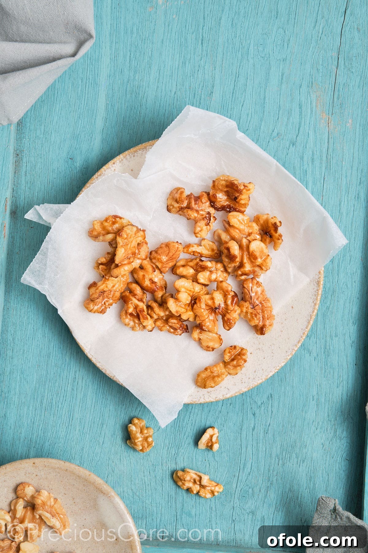 Cooling caramelized walnuts spread evenly on parchment paper.