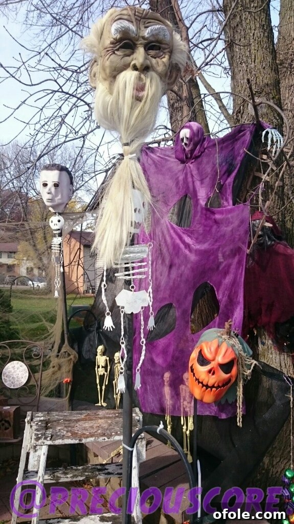 A residential house adorned with Halloween decorations, featuring glowing pumpkins, skeletal figures, and eerie lighting to create a spooky atmosphere.