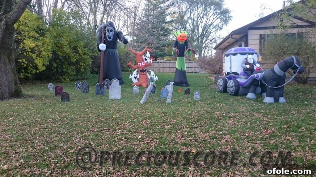 Another creatively decorated house for Halloween, showcasing a collection of ghosts, gravestones, and spiderwebs draped across the facade and lawn.