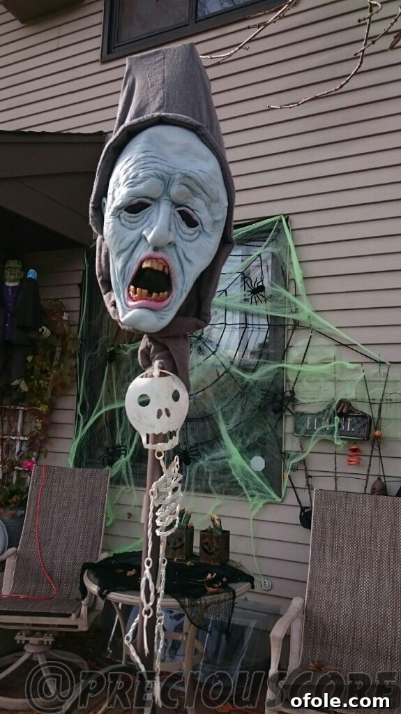 A close-up view of a Halloween decoration, possibly a detailed reaper figure or a haunted prop, adding a chilling touch to a front yard display.