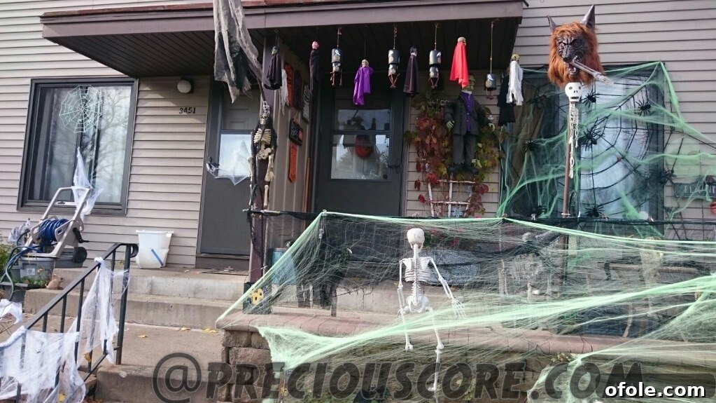 An outdoor Halloween display heavily featuring artificial cobwebs, possibly with large fake spiders, enhancing the eerie and abandoned look.