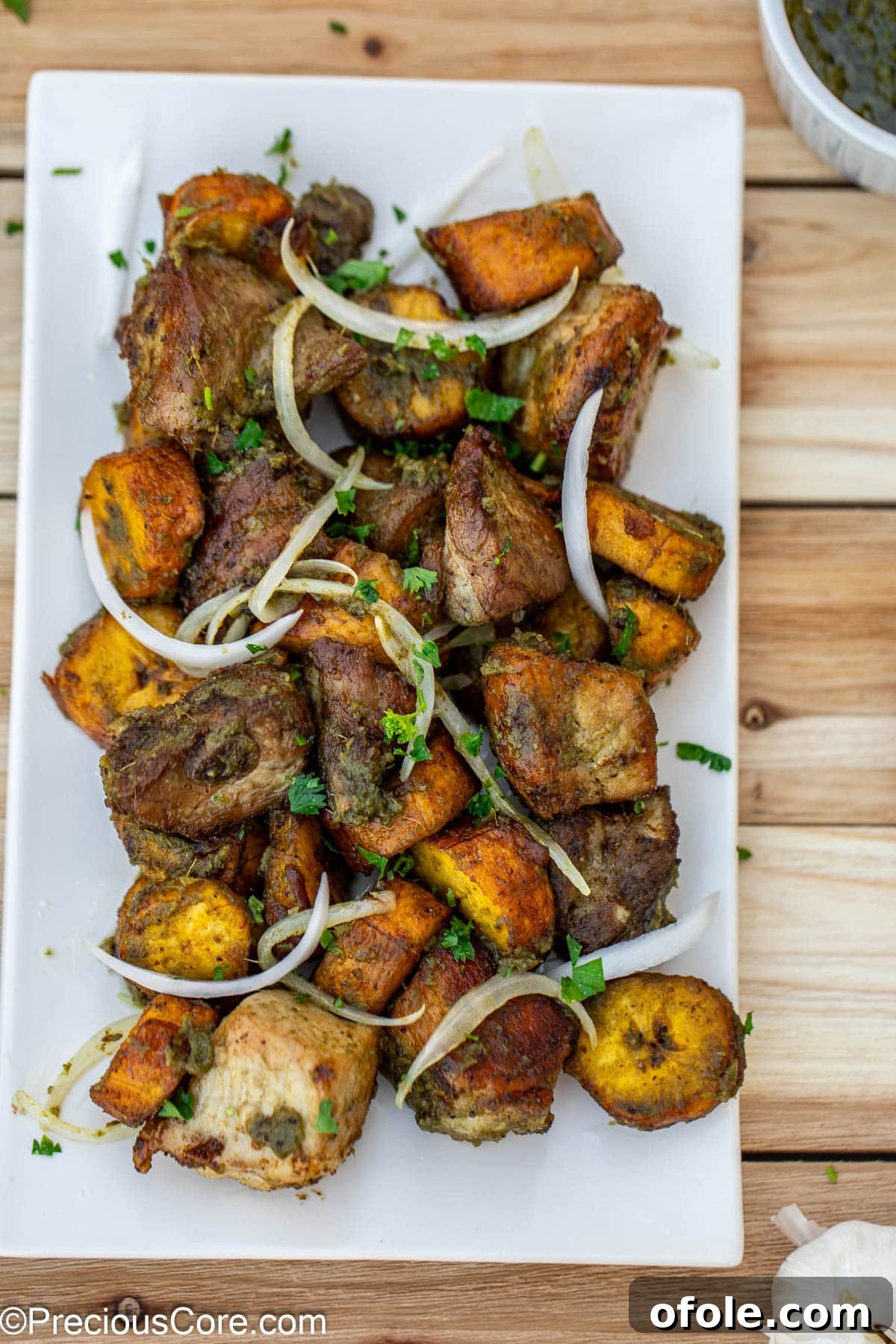 Crispy Pork with Golden Plantains 2 Crispy fried pork and golden plantains served on a platter, garnished with thinly sliced onions.