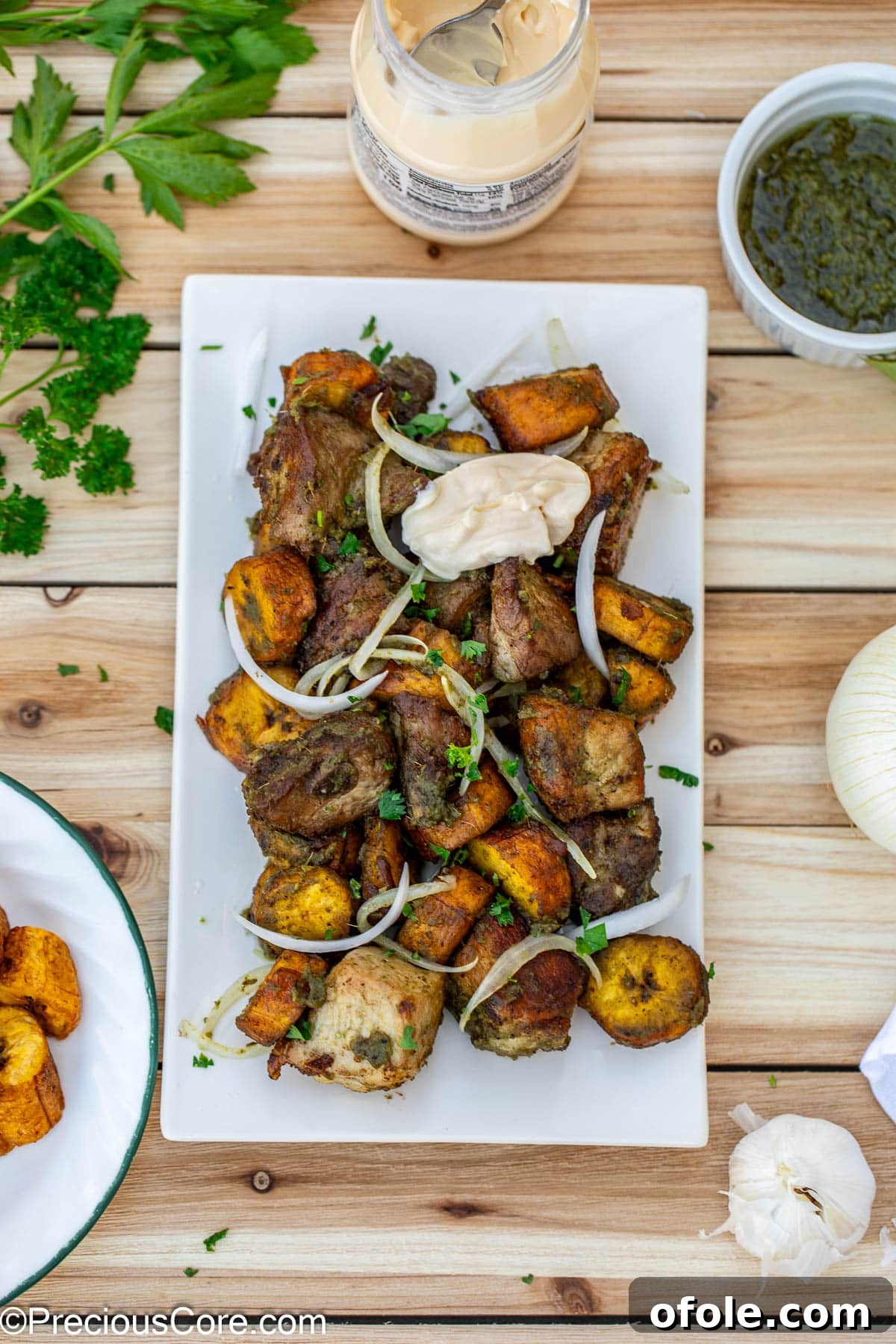 Crispy Pork with Golden Plantains 3 Round pieces of plantains and bite-size pork on a serving platter.