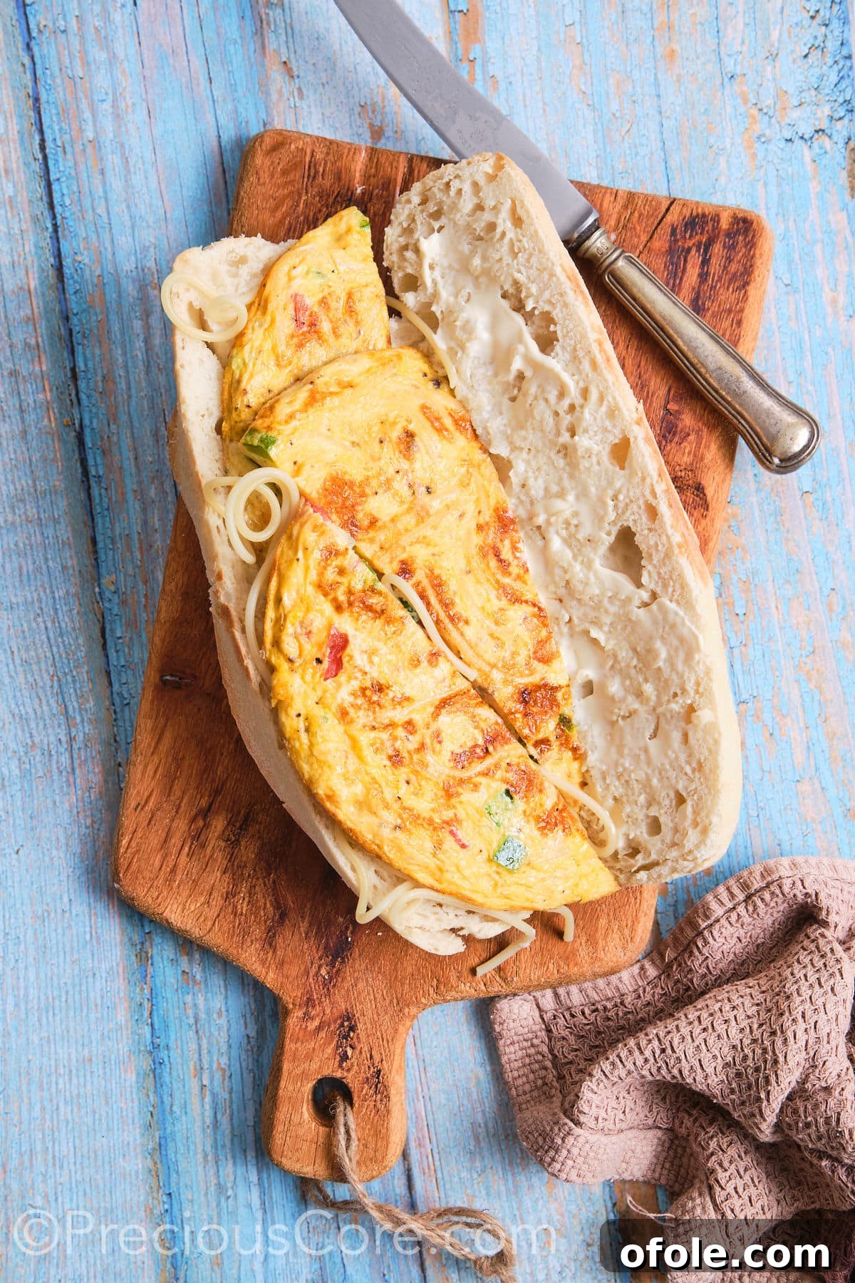 Cameroon's Signature Spaghetti Omelette Sandwich 11 Slices of spaghetti omelette carefully placed on one side of an opened baguette, preparing the sandwich.
