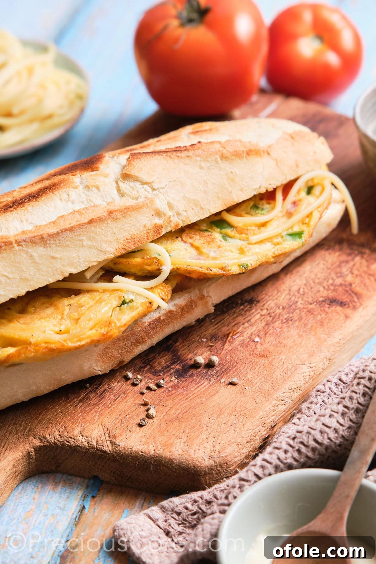 Cameroon's Signature Spaghetti Omelette Sandwich 12 A complete spaghetti omelette sandwich presented on a cutting board, ready to be served.