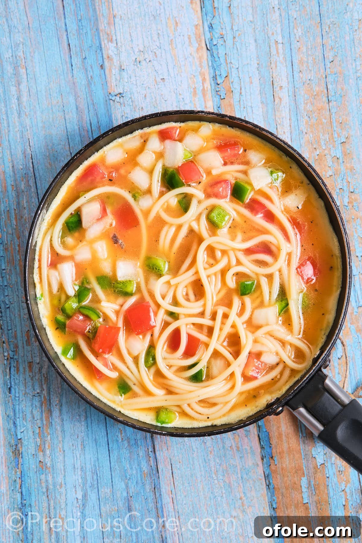 Cameroon's Signature Spaghetti Omelette Sandwich 7 A spaghetti omelette gently cooking in a medium skillet, covered to ensure even cooking.