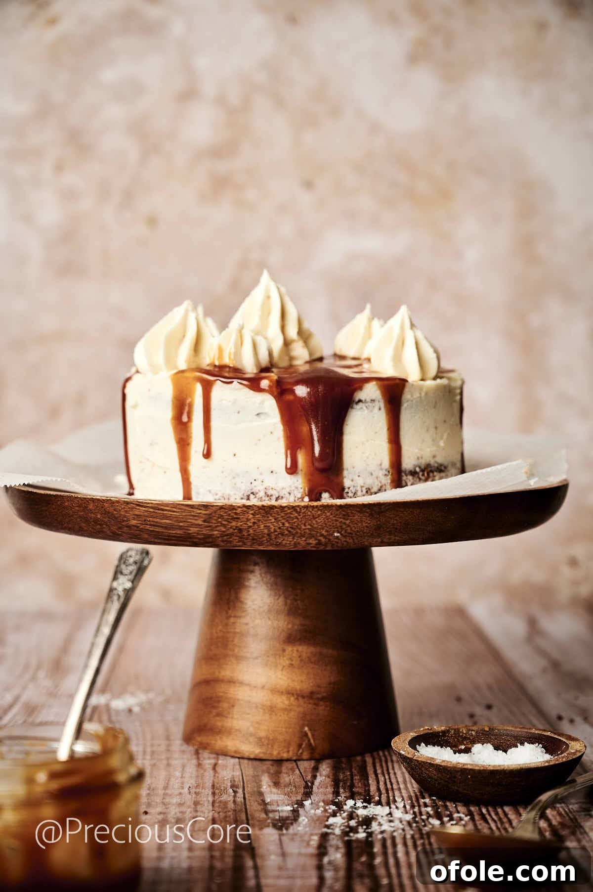 Salted Caramel Dream Cake 5 An exquisitely decorated cake with smooth white frosting and enticing caramel drips cascading down its sides, sitting on a graceful cake stand.