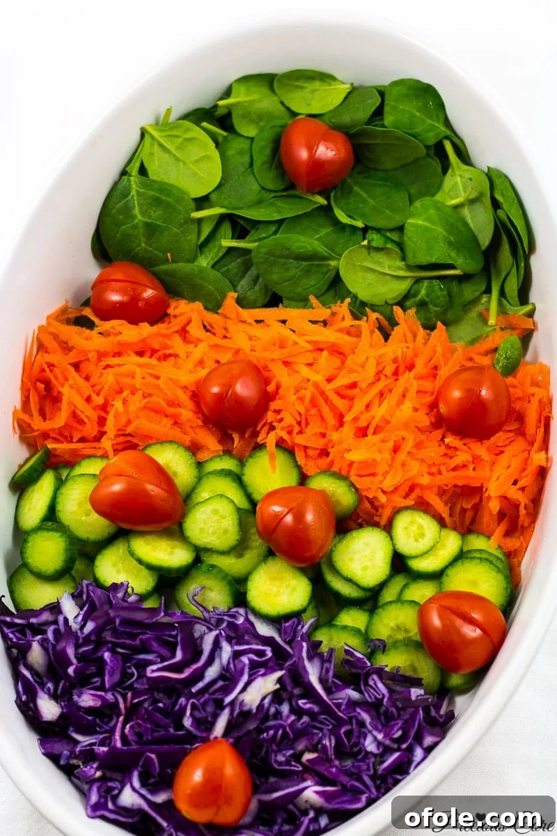 Crimson & Emerald Harvest 5 A visually stunning and fresh spinach and red cabbage salad, generously layered with shredded carrots and crisp cucumber slices, awaiting its vibrant honey lemon dressing