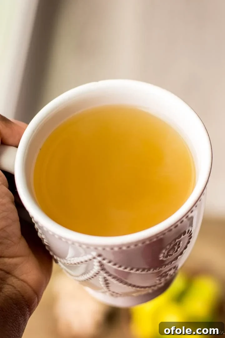 Zesty Ginger Brew 5 A hand holding a steaming mug of ginger tea, conveying warmth and comfort and the health benefits it offers.