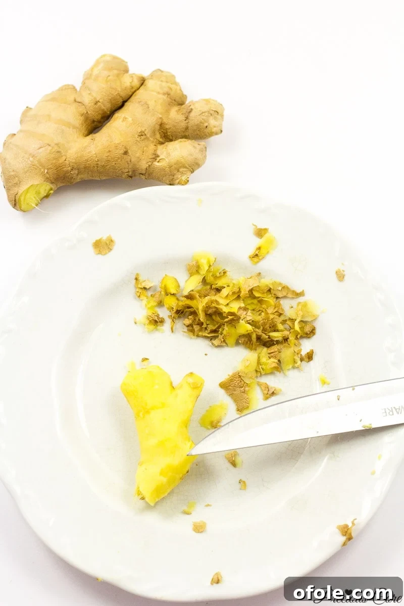 Zesty Ginger Brew 7 Peeled ginger root resting on a white plate, showcasing its readiness for the next step in the ginger drink recipe.