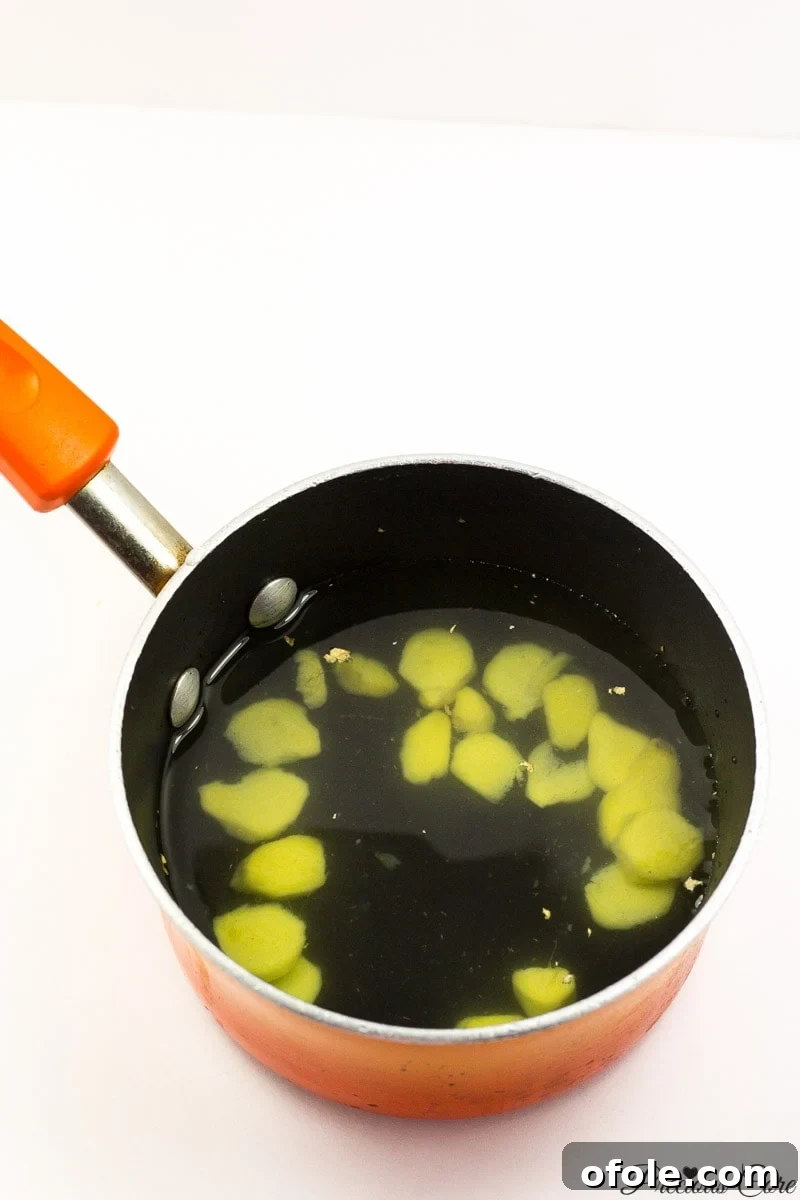 Zesty Ginger Brew 8 Sliced peeled ginger being placed into a pot with water, illustrating the initial stage of making ginger tea.