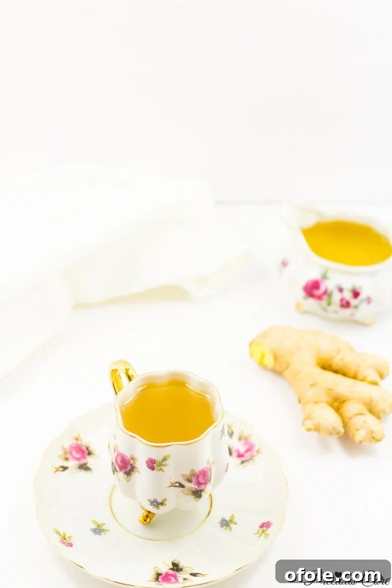 Zesty Ginger Brew 9 A freshly brewed ginger tea, sweetened and served in a glass mug, with a spoon for stirring.