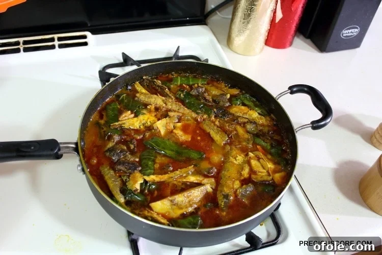 A large pot filled with cooked Ekwang, steaming gently, with the rich orange sauce and green parcels clearly visible, ready to be served.