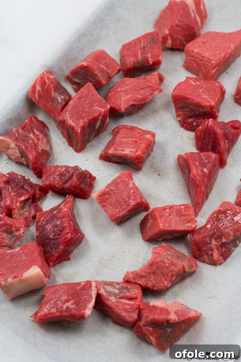 African Smokehouse Secrets: Mastering Home Meat Smoking 2 Cubed beef on a lined baking sheet, perfectly prepped for oven smoking to enhance flavor.