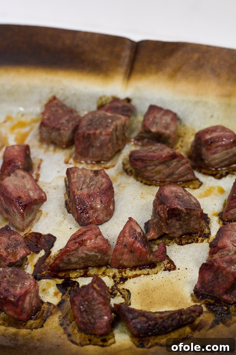 African Smokehouse Secrets: Mastering Home Meat Smoking 3 Perfectly cooked and oven-smoked beef slices on a lined baking sheet, ready for incorporation into African dishes.
