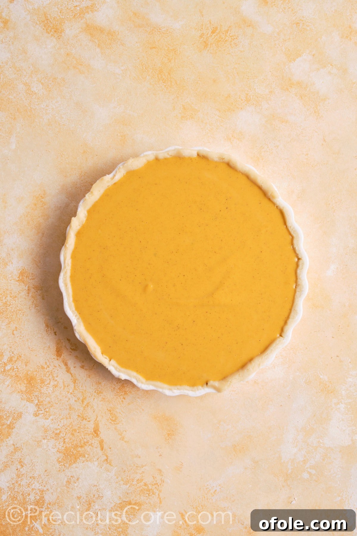 Creamy Pumpkin Pie Without Evaporated Milk 15 Smooth, orange pumpkin pie filling being poured into the unbaked, crimped pie crust within a white ceramic dish.