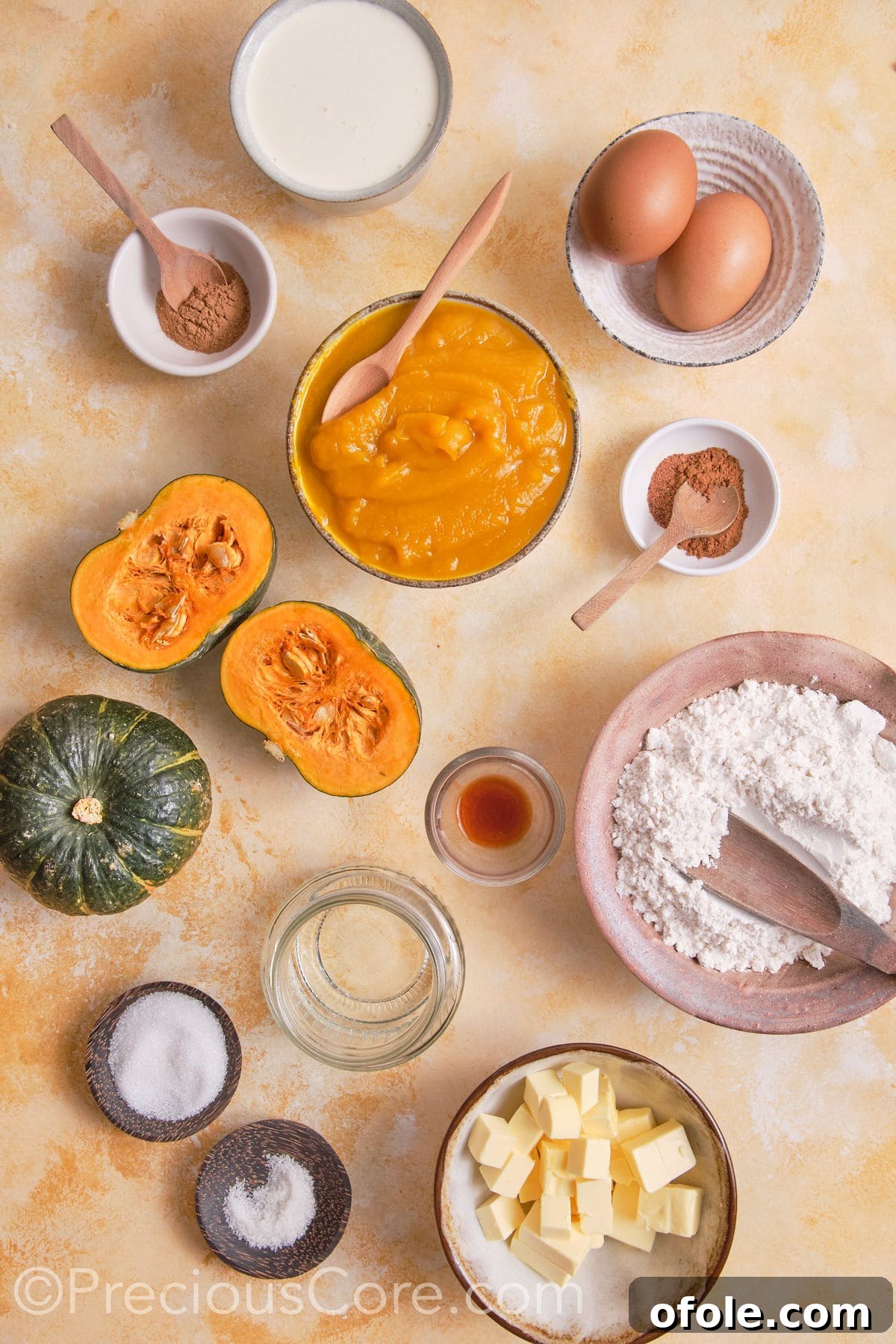 Creamy Pumpkin Pie Without Evaporated Milk 4 A selection of raw ingredients laid out on a wooden surface, including flour, sugars, butter, pumpkin puree, eggs, heavy cream, and various spices for making pumpkin pie.