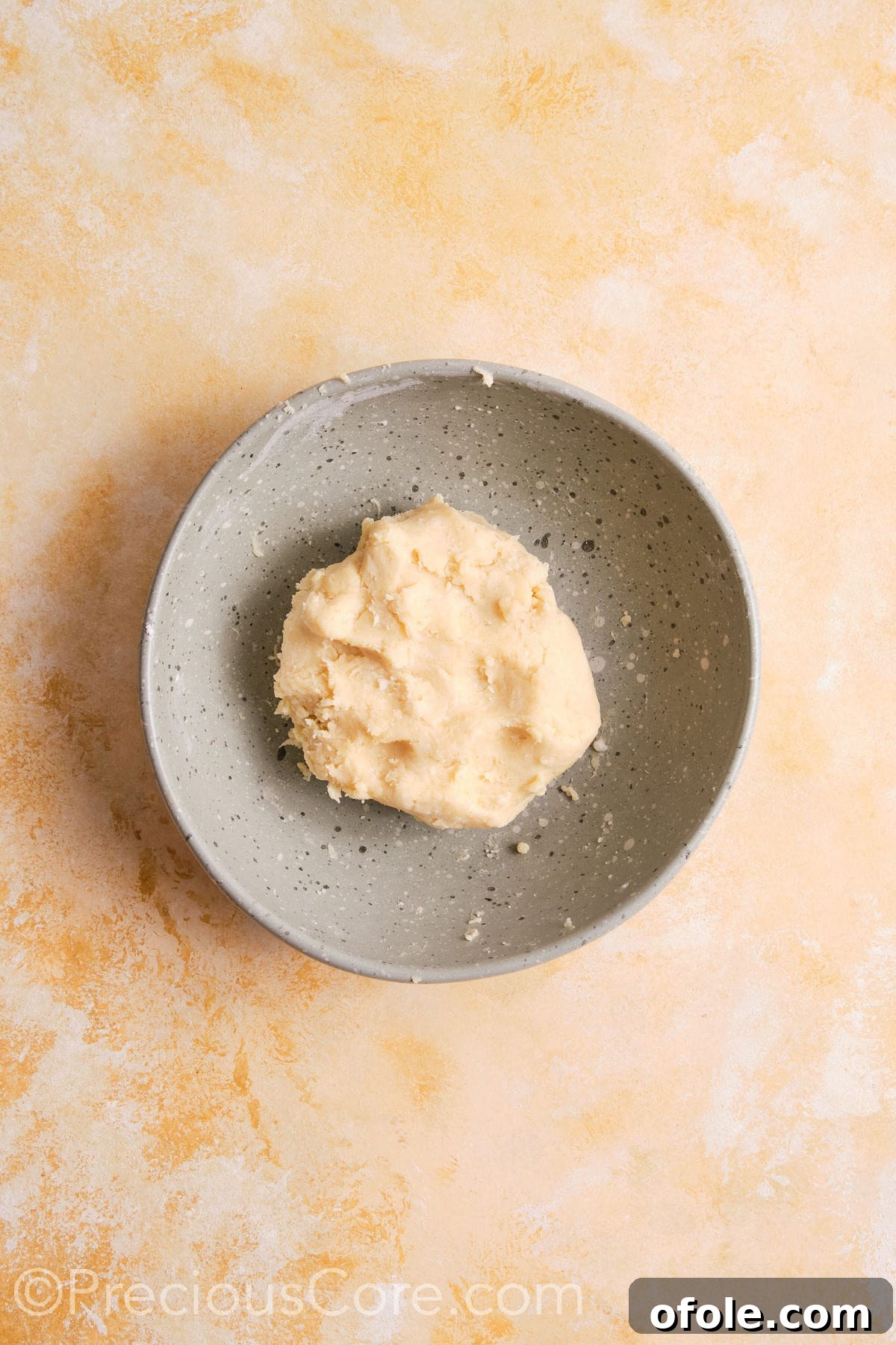 Creamy Pumpkin Pie Without Evaporated Milk 9 Pie crust dough in the process of coming together in a mixing bowl, showing a slightly shaggy but cohesive texture.