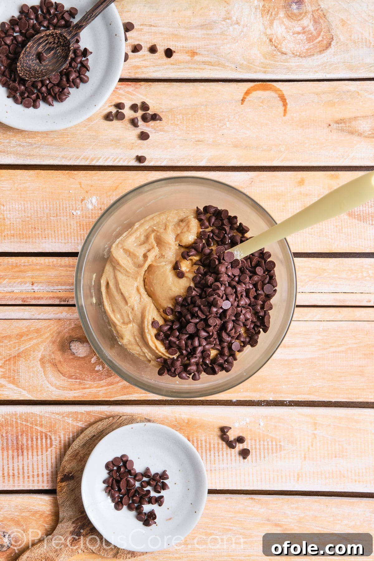 adding chocolate chips to the cookie dough mixture in a bowl. 