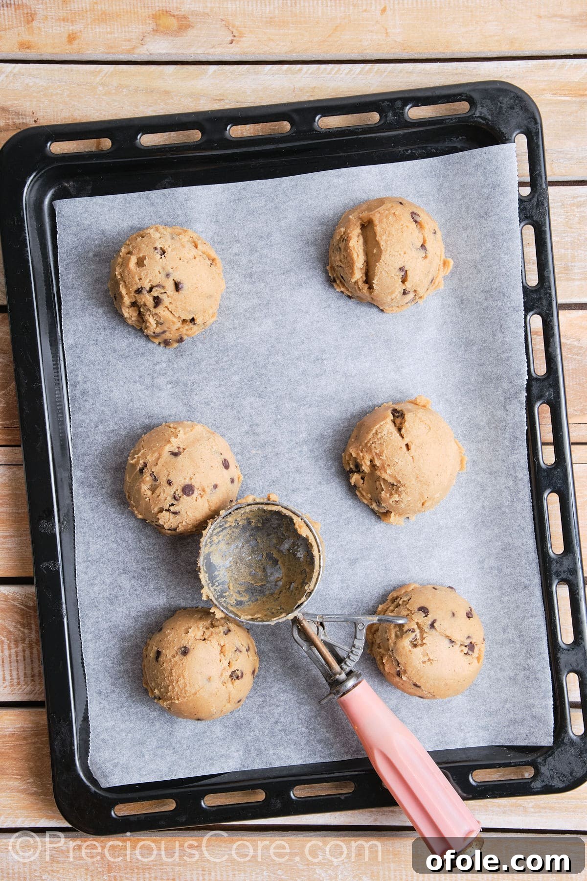 Baking sheet lined with parchment paper with 6 scoops of cookie dough