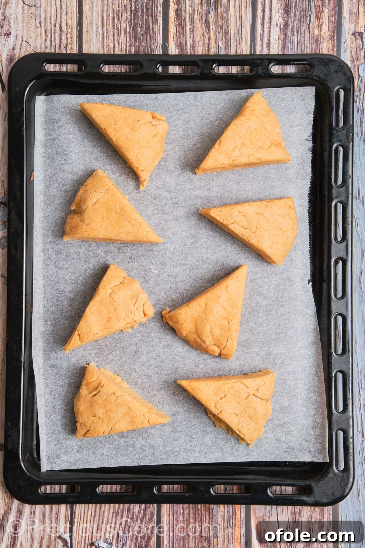 Golden Sweet Potato Scones 14 Unbaked sweet potato scone triangles neatly arranged on parchment paper on a baking sheet, spaced for even baking.