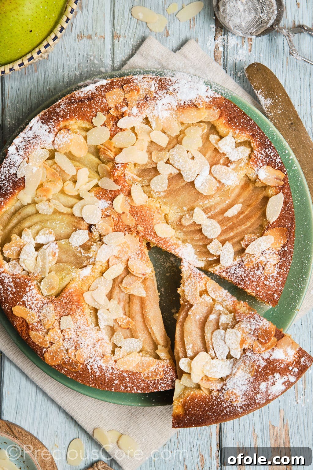 A beautifully presented Italian pear almond cake on a plate with a slice already cut out, showcasing its moist interior and fruit filling.