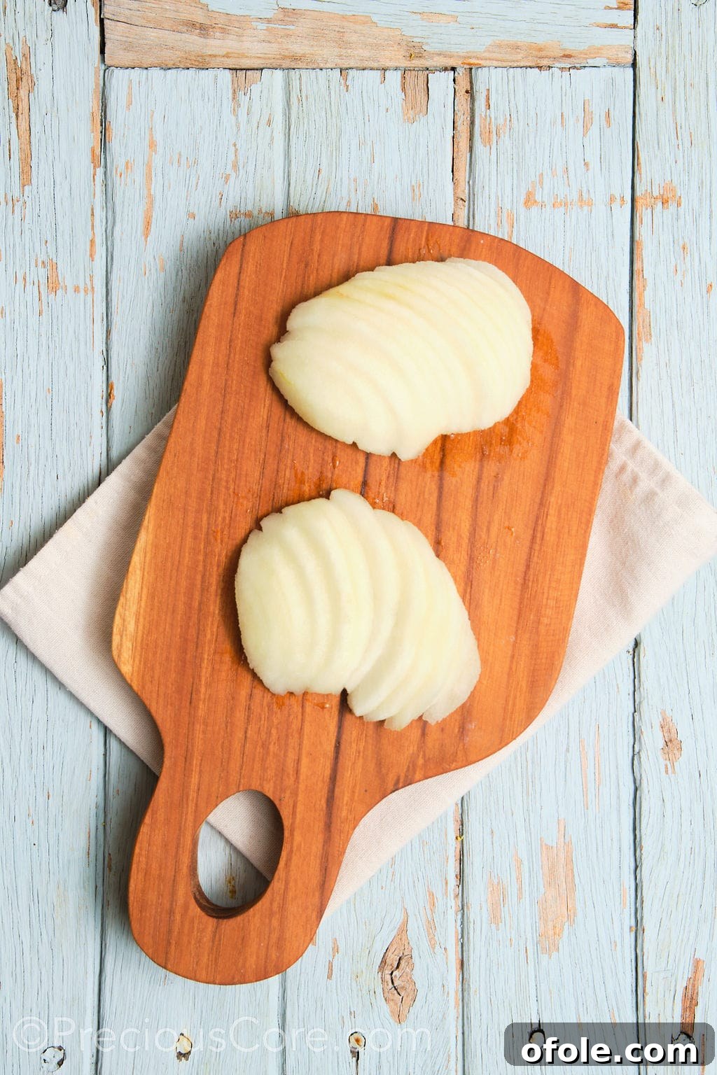 Thinly and uniformly sliced fresh, ripe pears arranged on a cutting board.