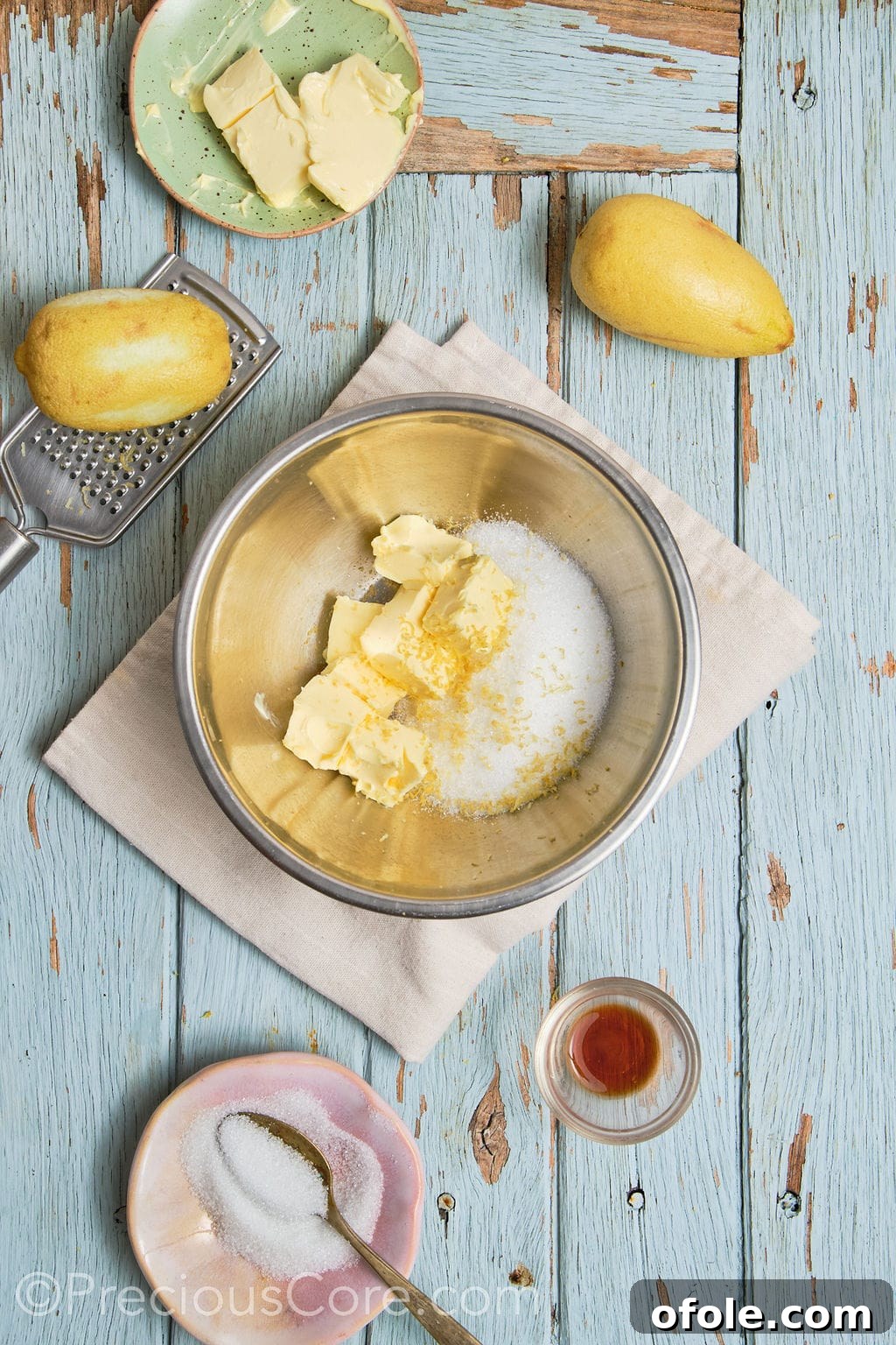 Softened butter, granulated sugar, and lemon zest being creamed together in a mixing bowl until light and fluffy.