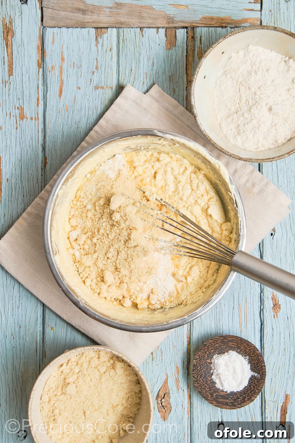 Almond flour and other dry ingredients being carefully folded into the wet cake batter using a spatula.